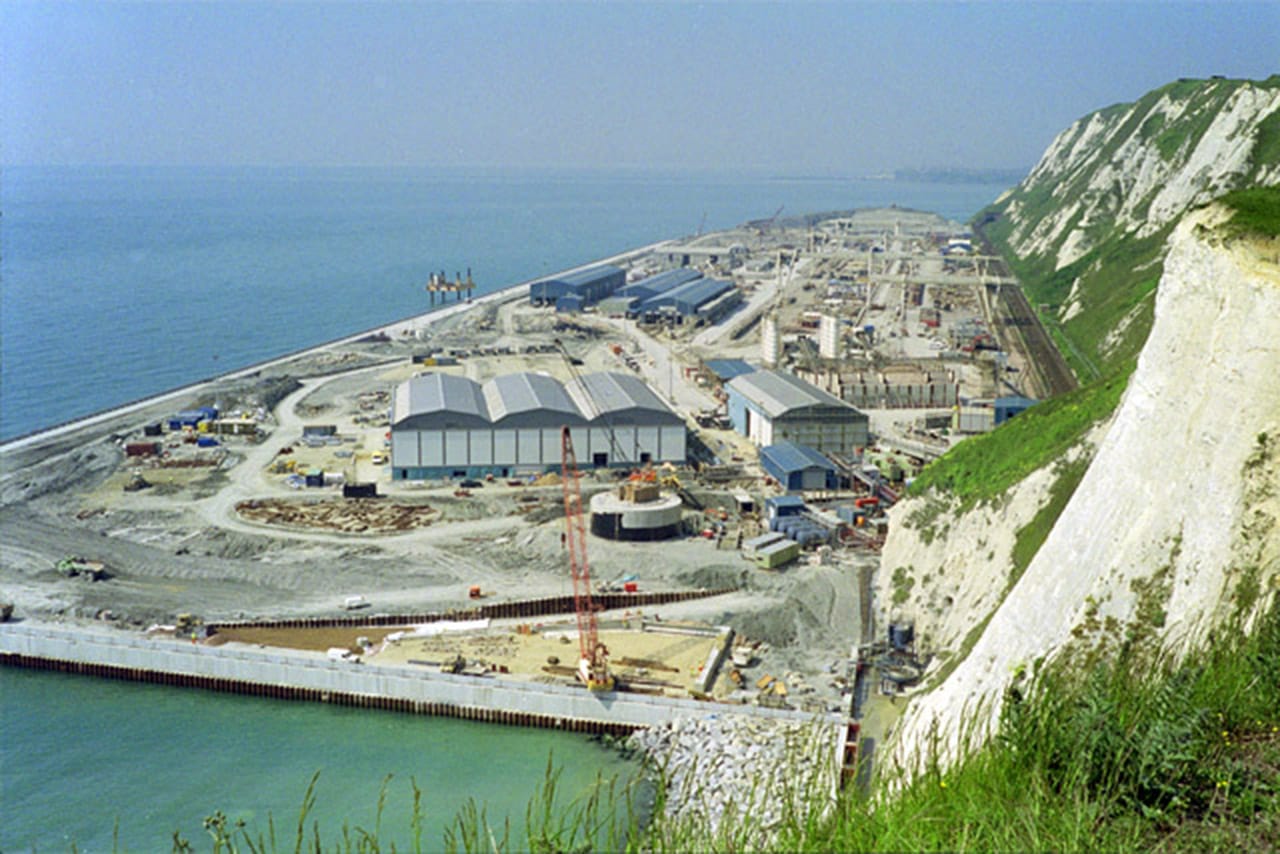 Channel Tunnel construction site, 1992. This shelf was built from tunnel spoil, and large parts of it were then used as the principal English depot for continued work. The tunnel was opened two years later, and most of this area was then landscaped into a nature reserve called Samphire Hoe. Attribution: Copyright Robin Webster and licensed for reuse under CC BY-SA 2.0